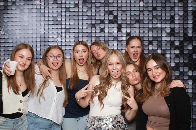Grote groep vriendinnen voor zilveren pailletten, iedereen steekt de tong uit