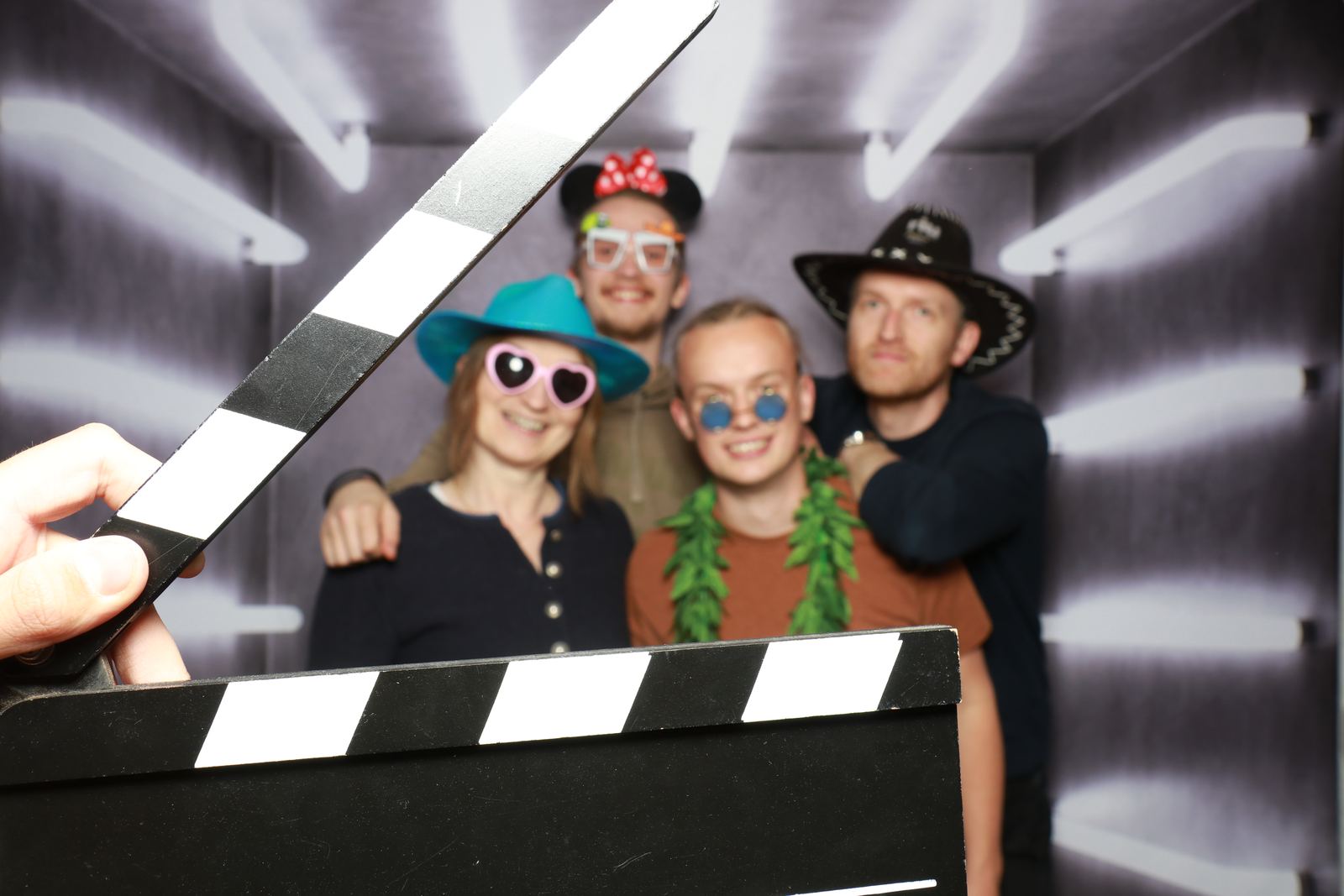 Een filmklapper voor de camera, daarachter een groep met hoedjes