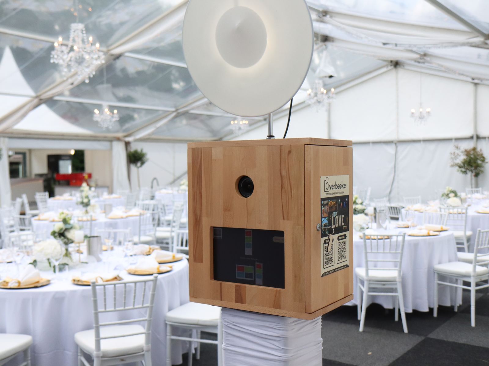 De houten Overbeeke photobooth in een feestelijk gedekte tent met kroonluchters