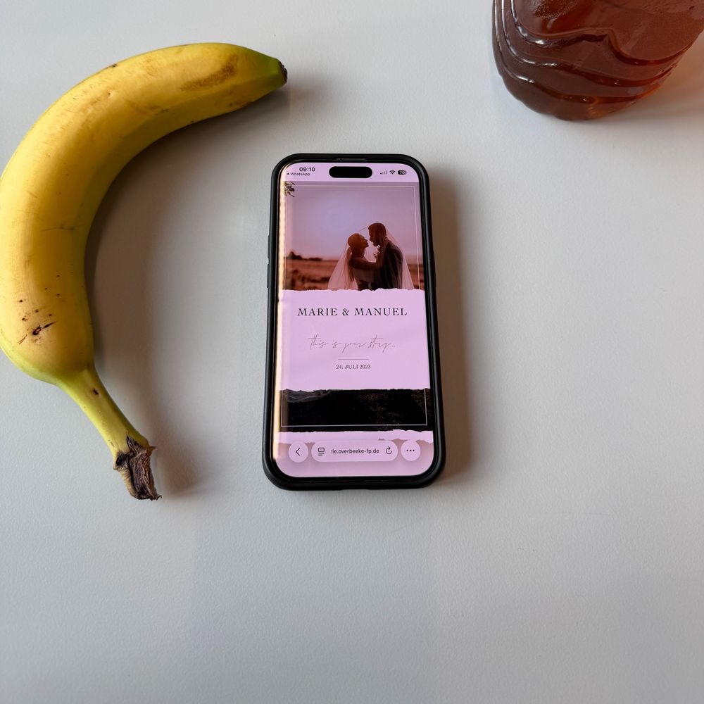 Smartphone met geopende online galerij op tafel, ernaast een banaan en ijsthee