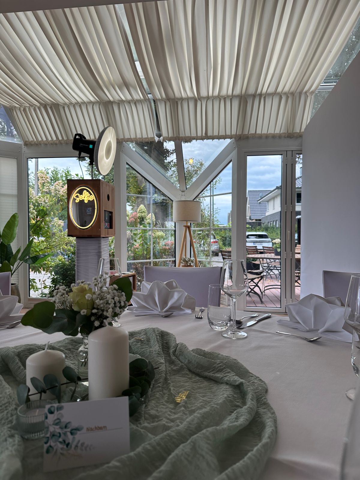 Bruiloftstafel in de wintertuin, daarachter de photobooth met selfie-lichtbord