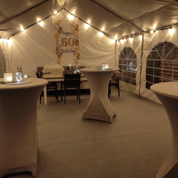 Partyzelt mit Lichterkette und Stehtischen am Abend