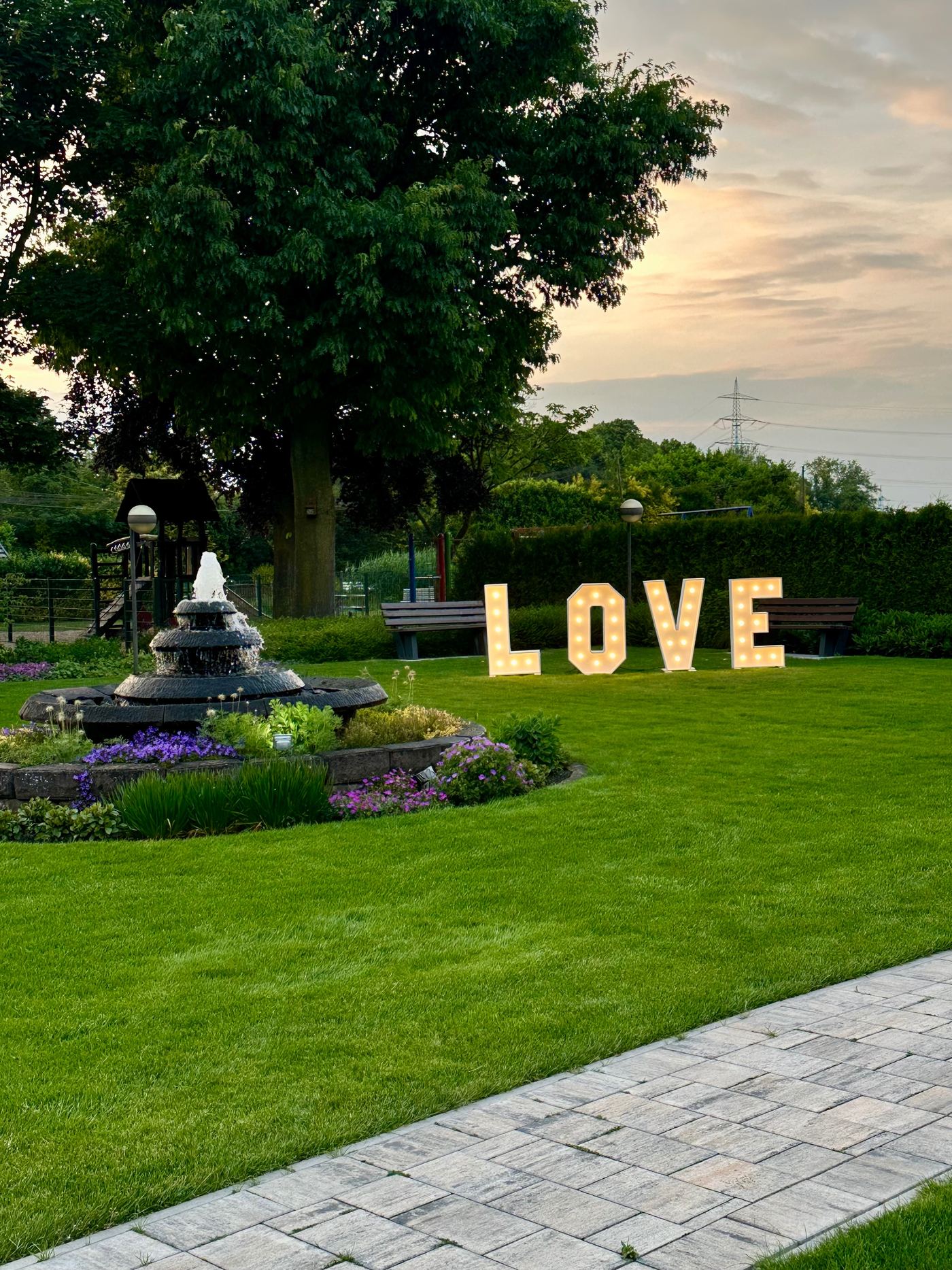 Leuchtende LOVE-Buchstaben auf einer Wiese bei Sonnenuntergang