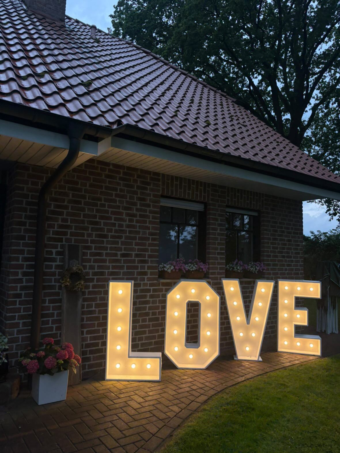 LOVE-Buchstaben vor einem Backsteinhaus in der Dämmerung
