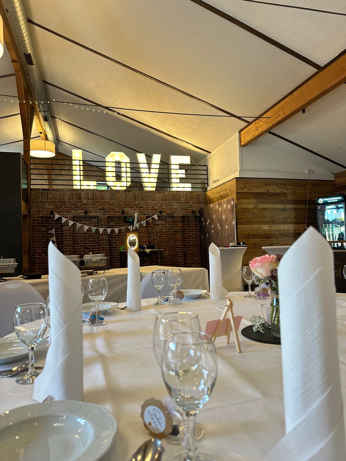 LOVE-Buchstaben auf der Empore einer Scheune über der Hochzeitstafel