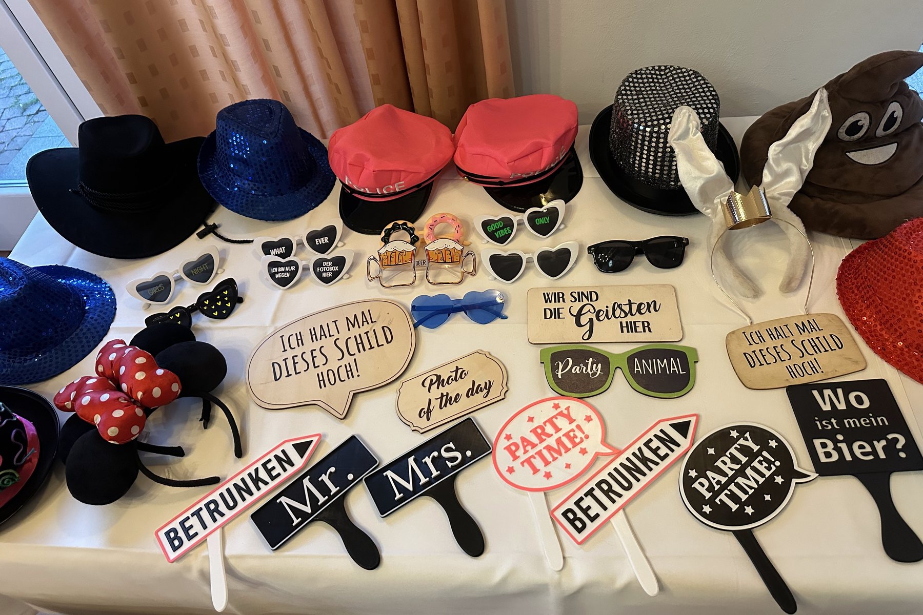 Tafel met props: hoeden, hartjesbrillen, diademen en bordjes zoals Party Time en Wo ist mein Bier